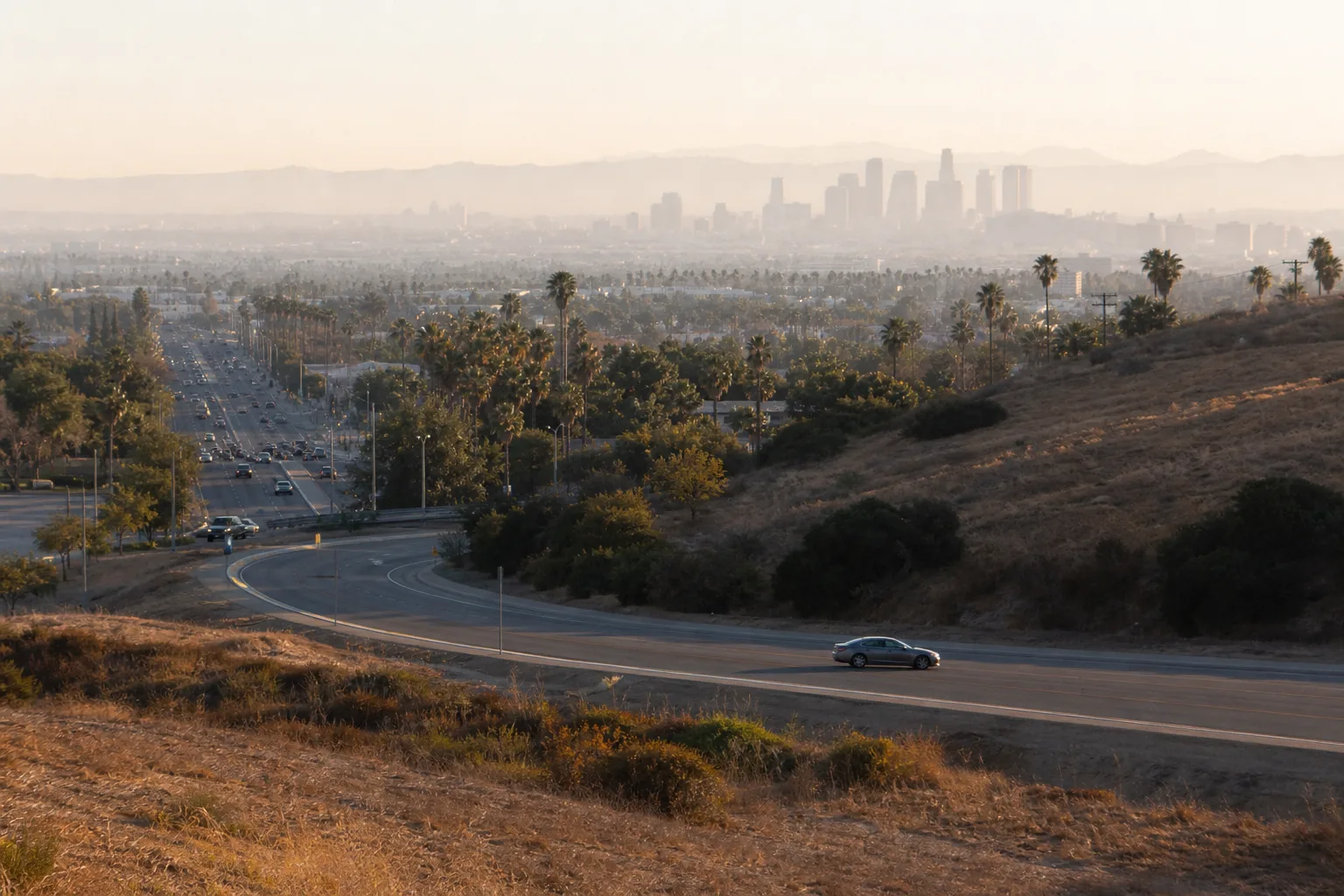 Hyrbil på en bred väg ut från Los Angeles mot Kaliforniens landskap